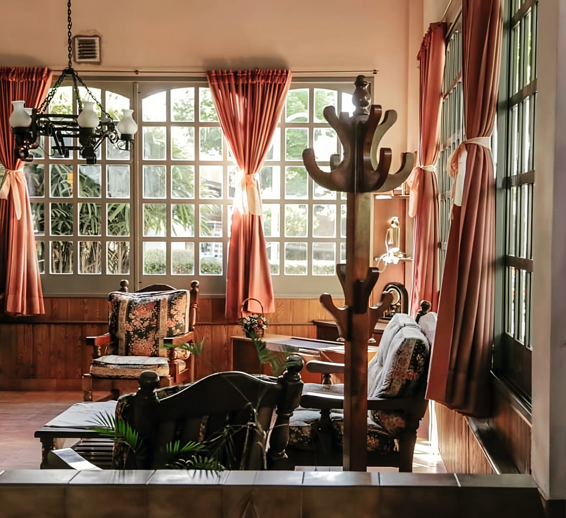 Living de la casa con ventanales, cortinas y muebles de madera