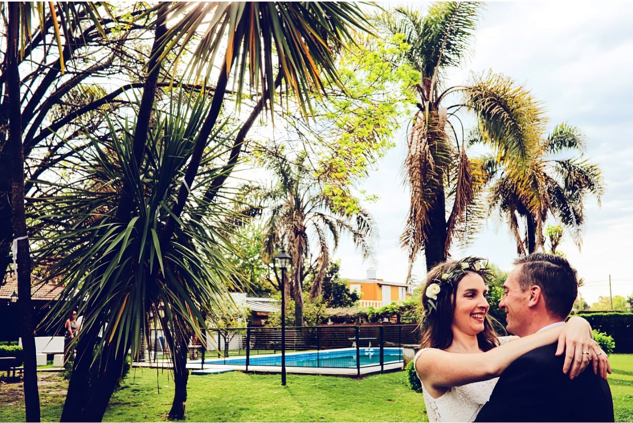 Novios abrazados entre palmeras en el parque de la quinta