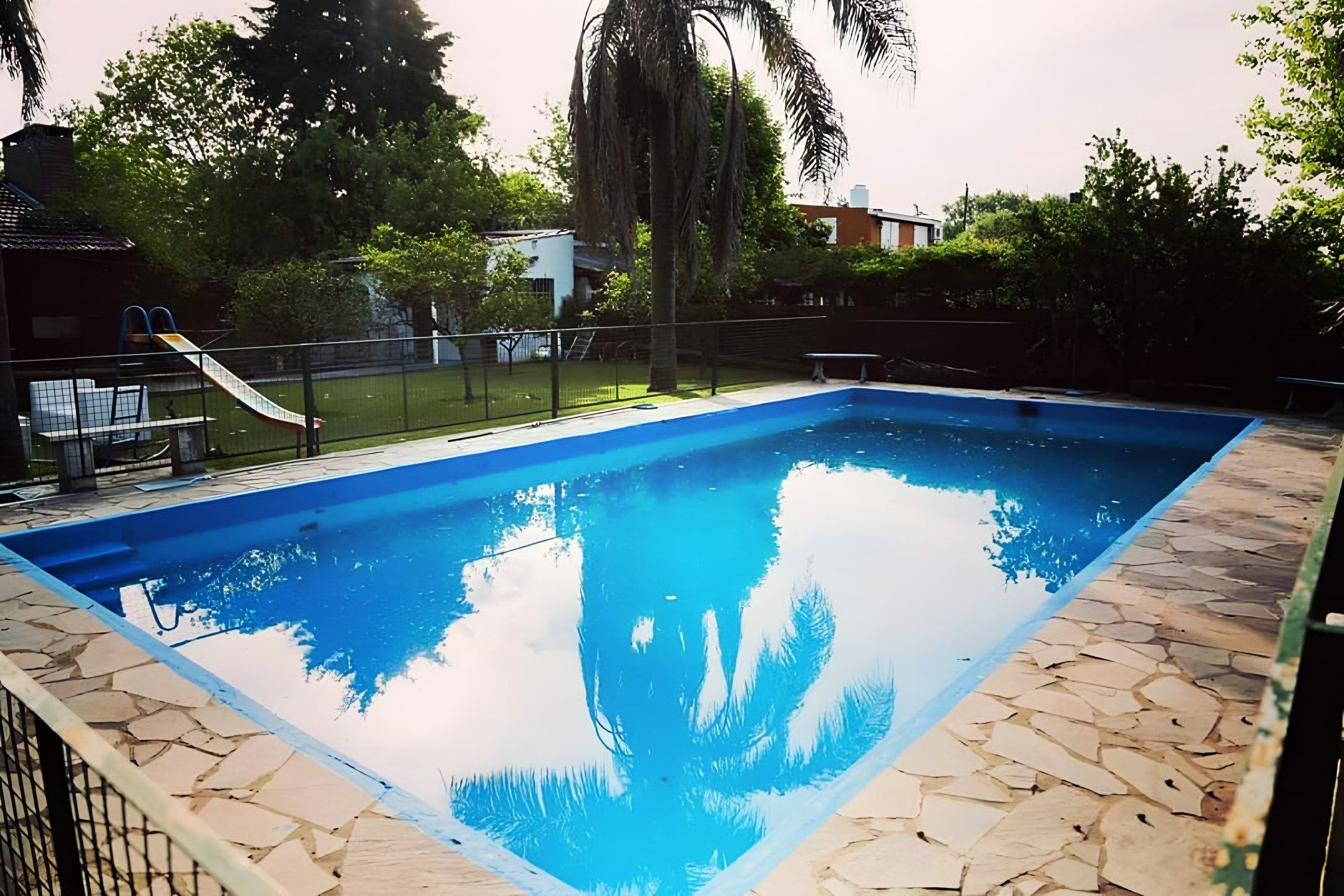 Pileta de la quinta con deck de piedra, parque y palmeras para el día de pile