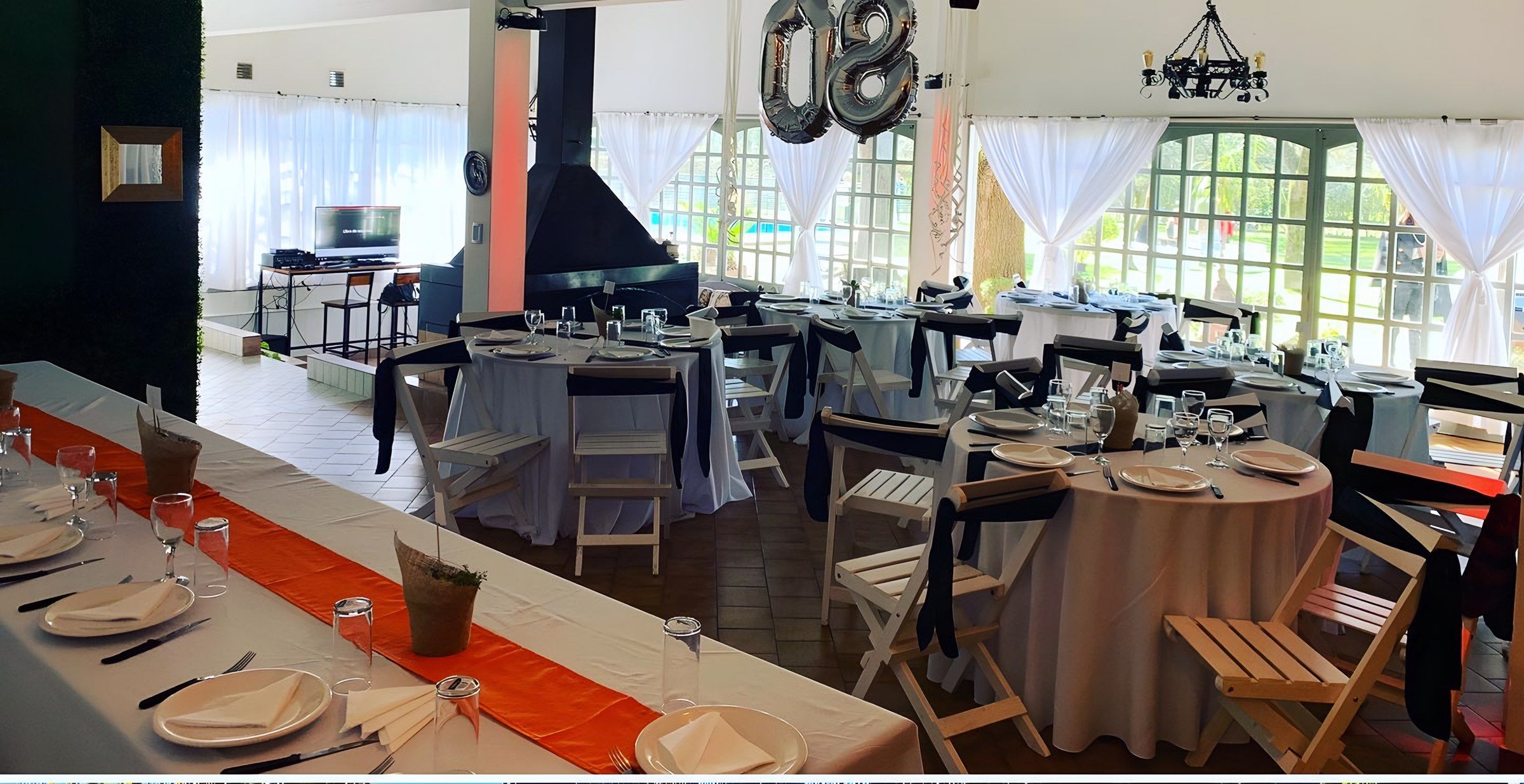 Salón cubierto con mesas armadas y ventanales al parque